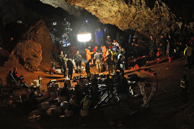 Thai lan2: Chuyên gia cứu hộ Thái Lan (áo cam) giúp một binh sĩ thăm dò một lối có thể xuống hang Tham Luang ngày 30/6/2018. Ảnh: AFP